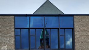Spiegelung des Turms von St. Magni in der Fassade der Edith-Stein-Schule