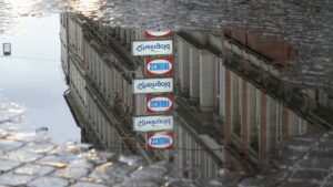 Spiegelung einer Leuchtreklame in einer Regenpfütze am Damm