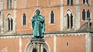 Figur Heinrich des Löwens auf dem Heinrichsbrunnen, im Hintergrund St. Katharinen