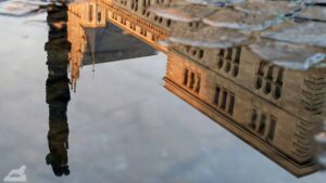 Spiegelung der Christussäule in einer Pfütze